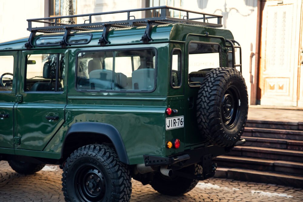 Green off-road vehicle with roof rack parked in city.