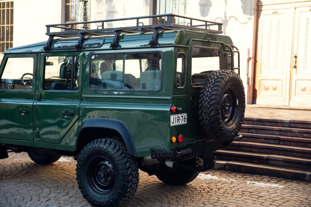 Green SUV parked near historic building.