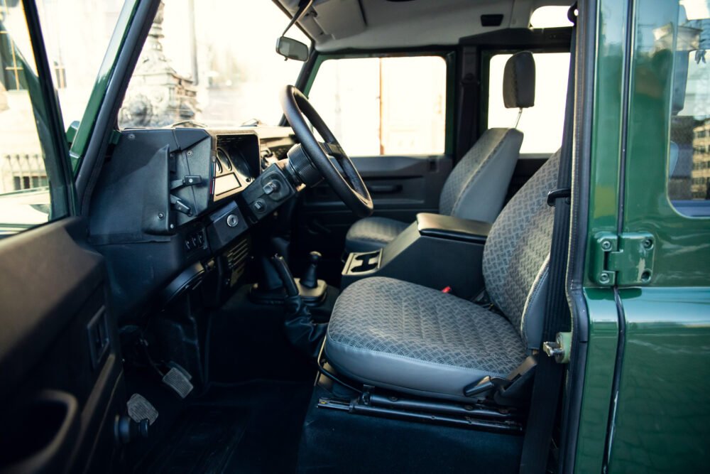 Interior view of vintage green vehicle's dashboard and seats.