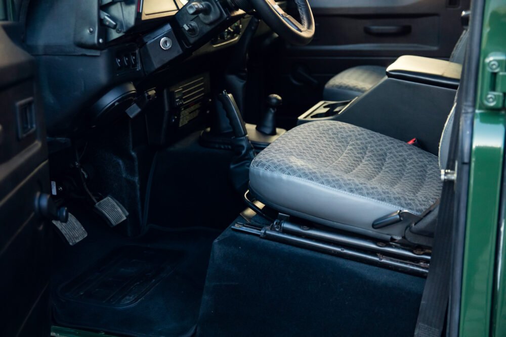 Interior view of green vehicle's front driver seat and dashboard.