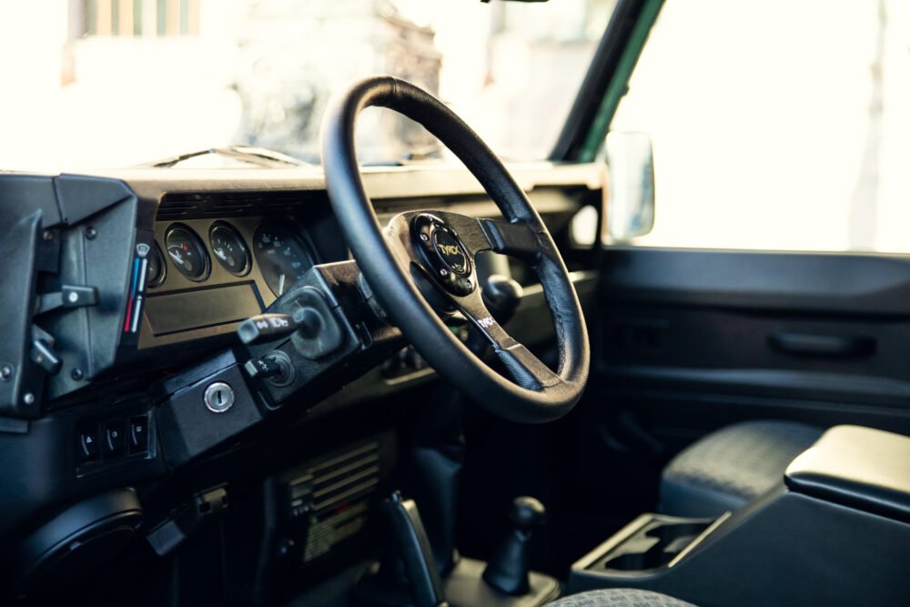 Interior view of an old vehicle's dashboard and steering wheel.