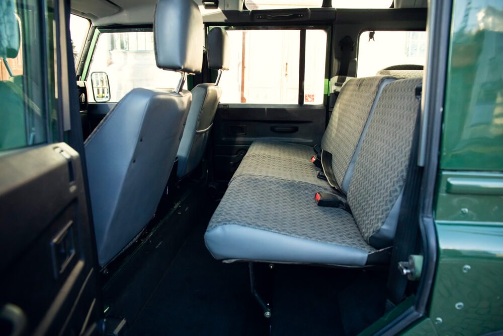 Interior of green van with seats and safety belts.