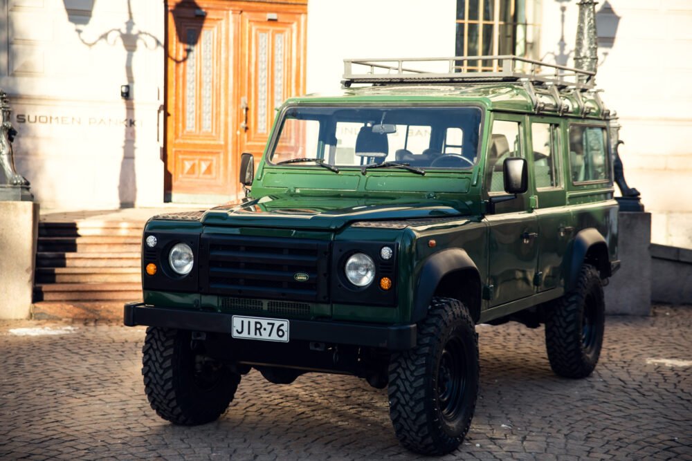 Green SUV parked by historic building.