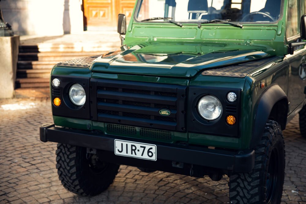 Green Land Rover Defender parked in urban area.