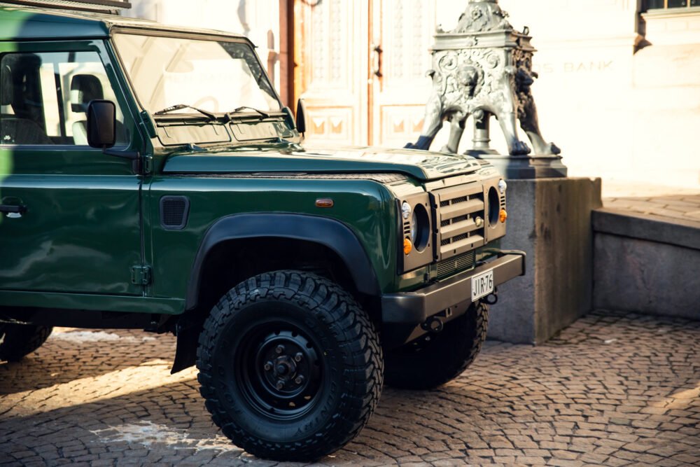 Green Land Rover near historic bank building.