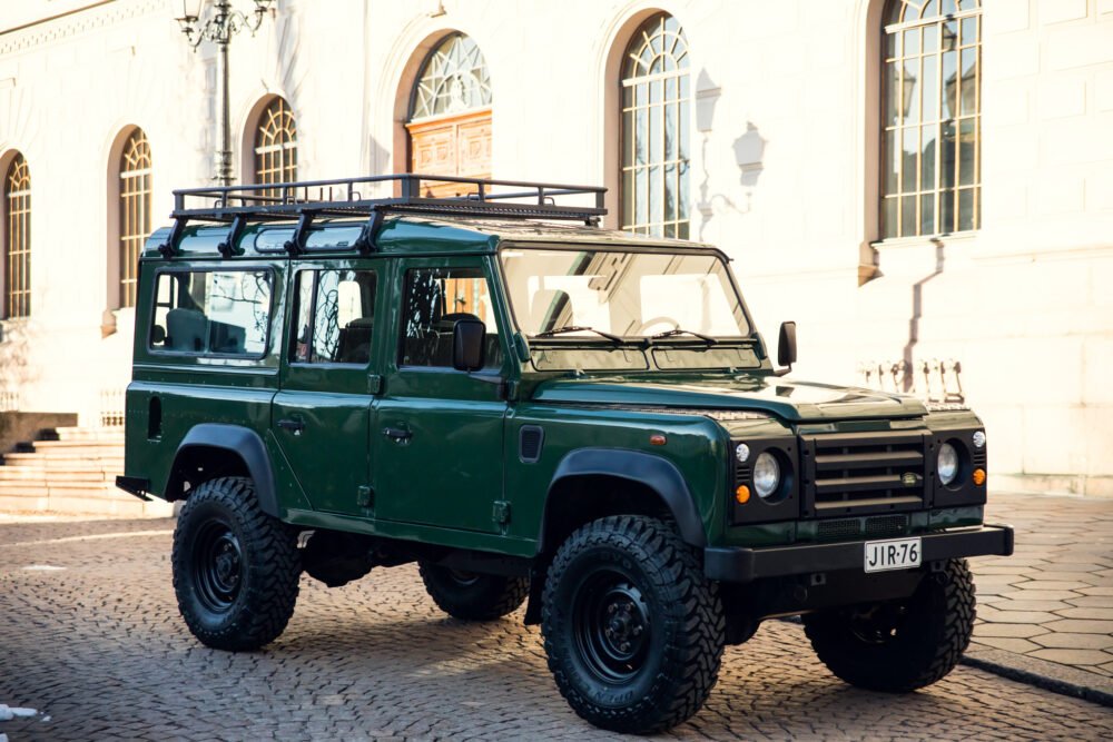 Green Land Rover Defender parked near historic building.