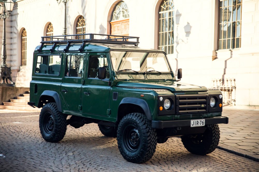 Green Land Rover Defender parked near historic building.