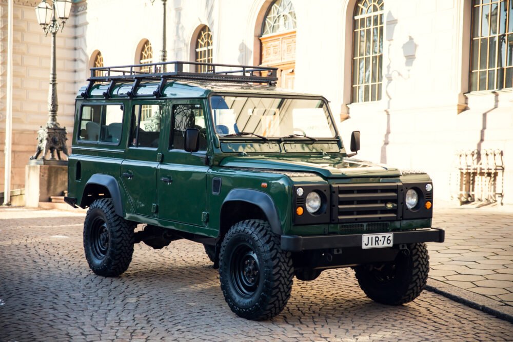 Green Land Rover parked in historic courtyard.