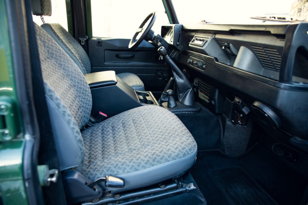 Vintage car interior with patterned seats and manual transmission.