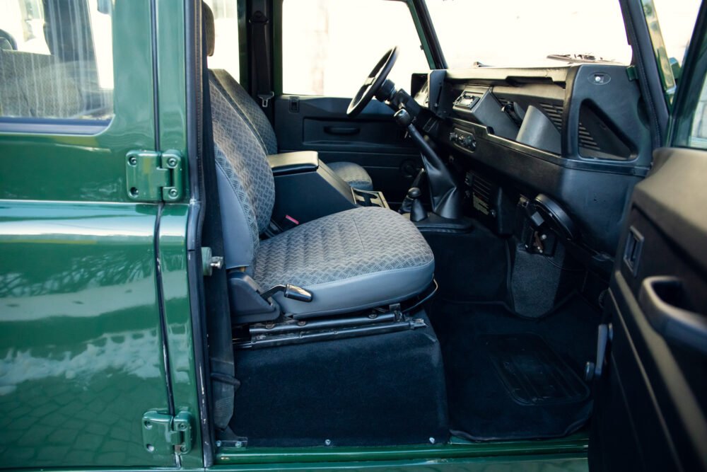 Interior view of vintage green vehicle with patterned seats.