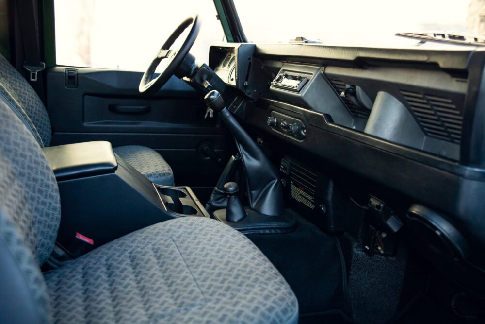 Interior of vintage car with steering wheel and gear shift.