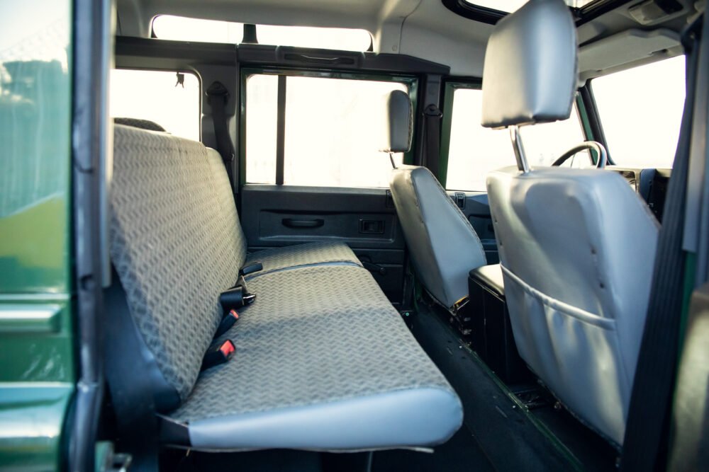 Interior of empty, sunlit vehicle with rows of seats.