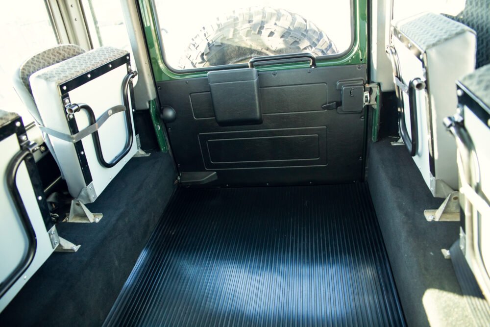 Interior of a green military vehicle with seats.