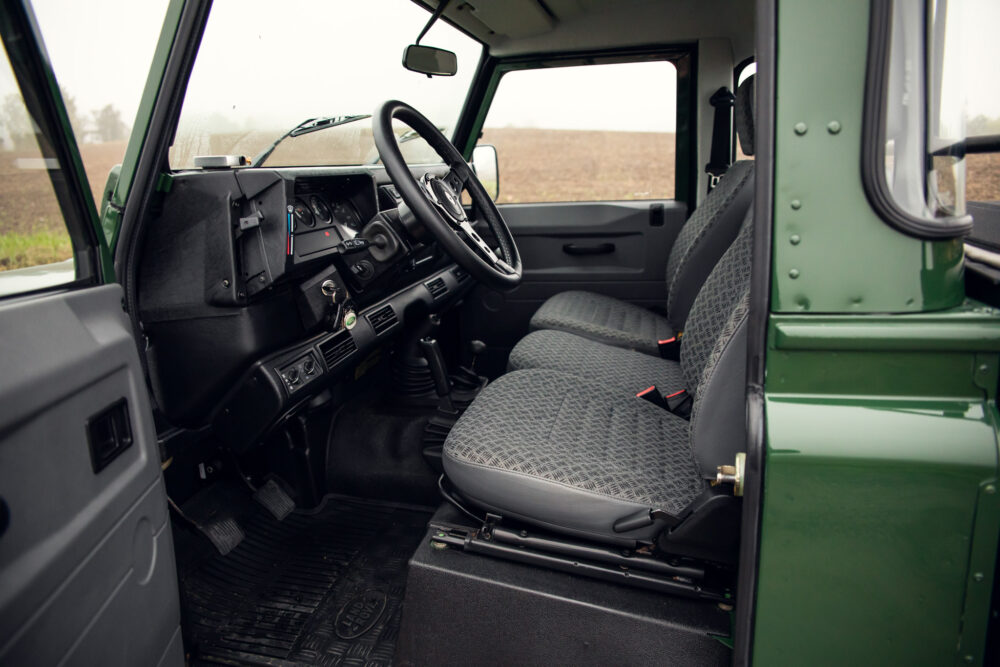 Interior of vintage green off-road vehicle with patterned seats.