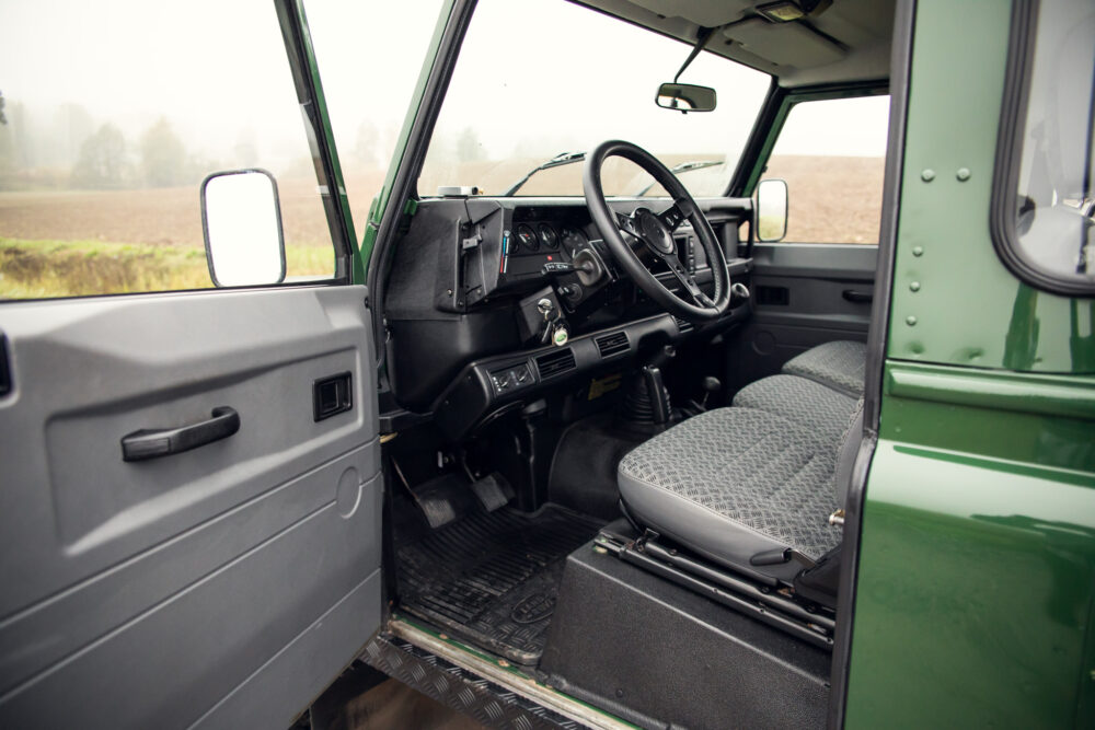 Interior of vintage green truck with open door.