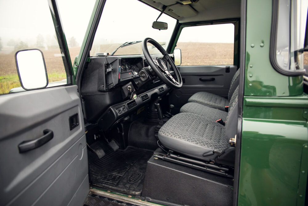 Interior view of vintage green SUV with open door.