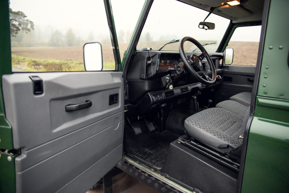 Interior of vintage green SUV with open door.