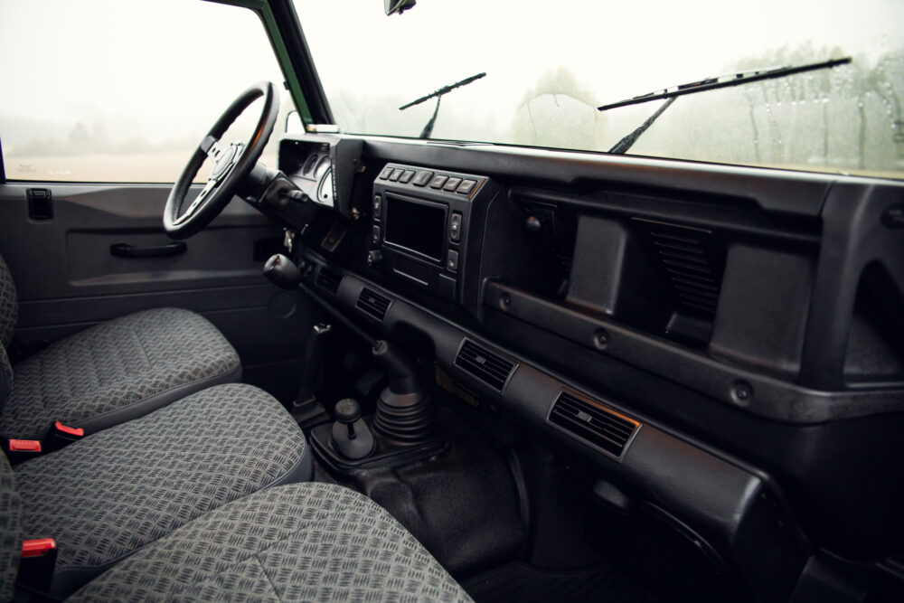 Vintage car interior with patterned seats and dashboard.