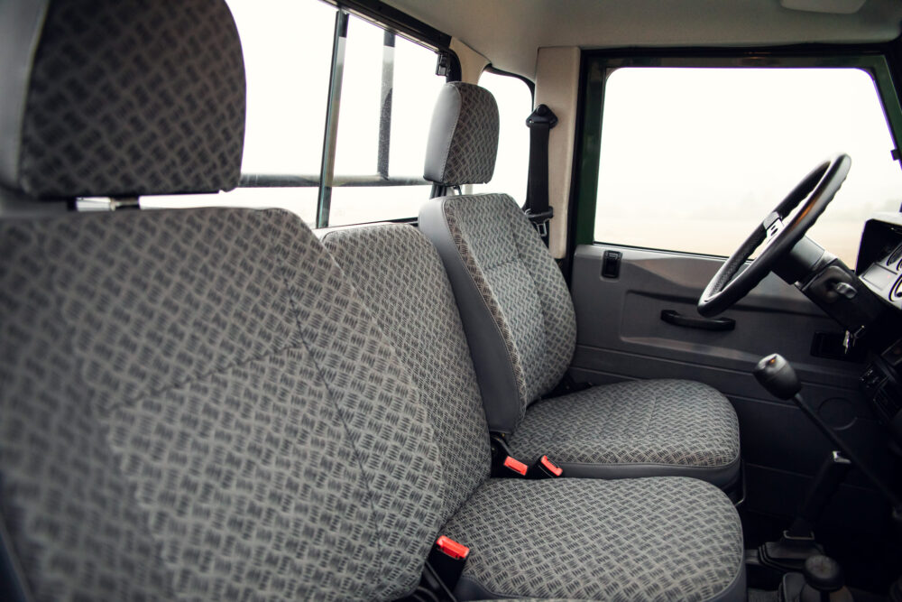 Interior view of empty patterned vehicle seats and steering wheel.