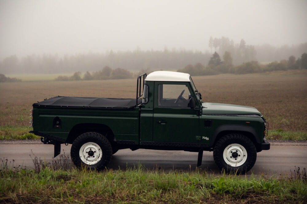 Green pickup truck on foggy rural road.