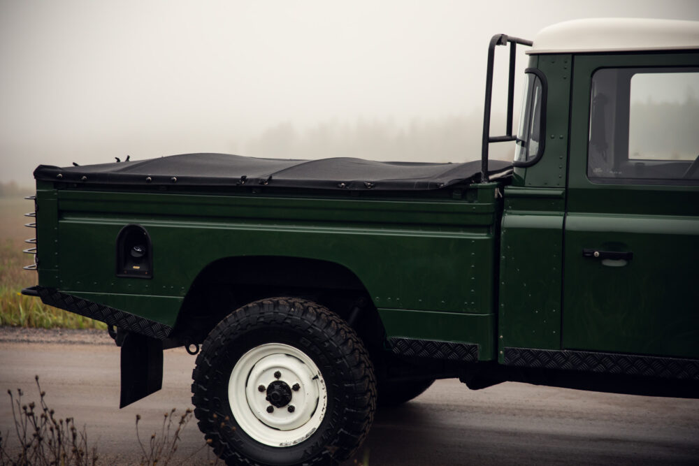 Green vintage off-road vehicle in foggy field.