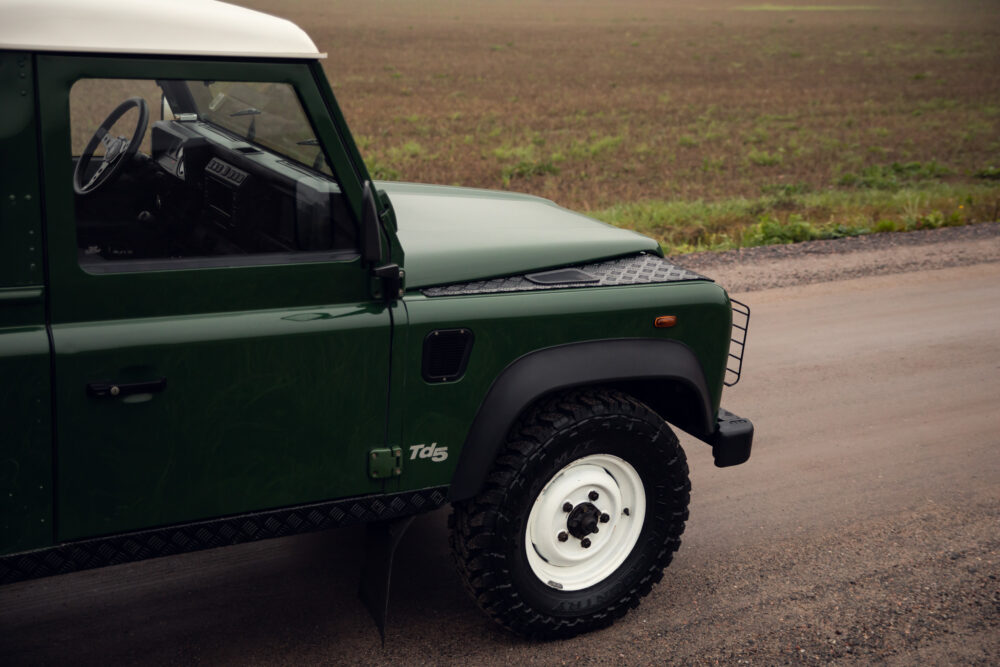 Green off-road vehicle parked on gravel road.