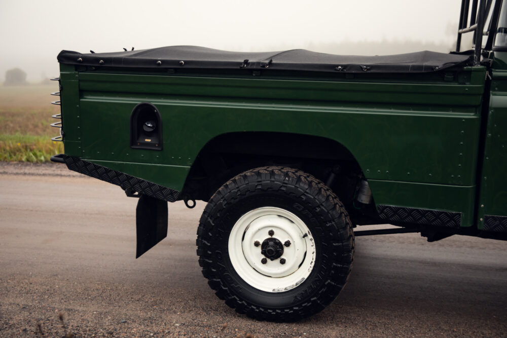 Green off-road vehicle on foggy rural road.