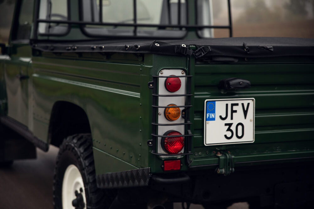 Green SUV with Finnish license plate and rear lights.