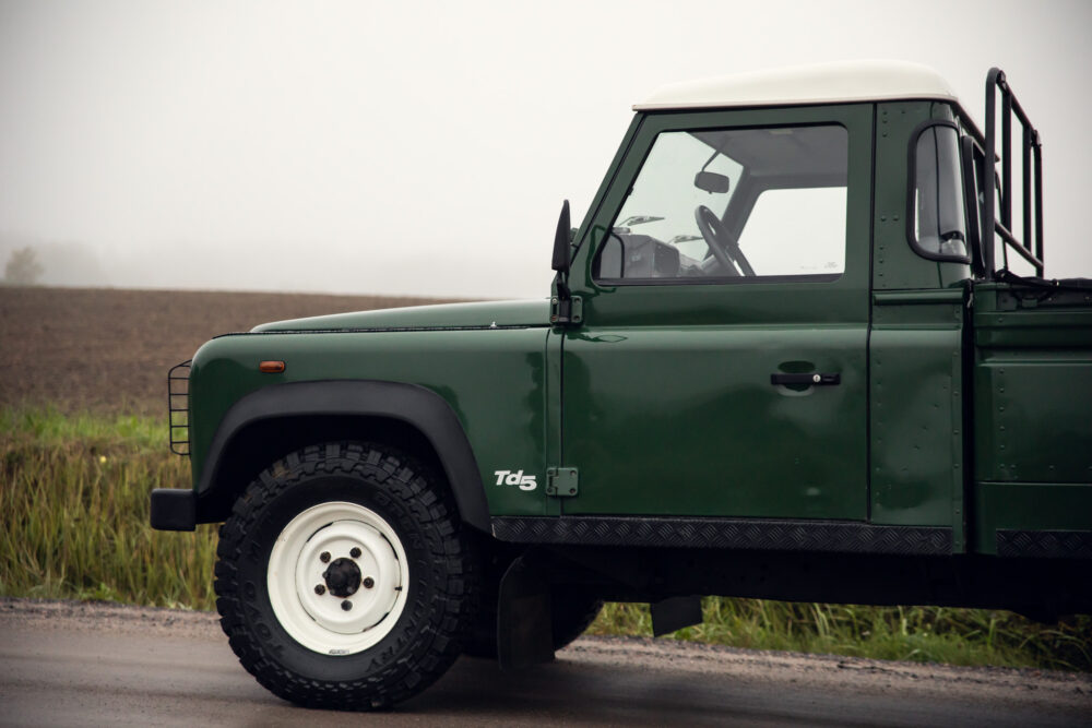 Green pickup truck on misty rural road.