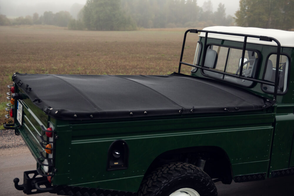 Green truck with covered bed in foggy field.