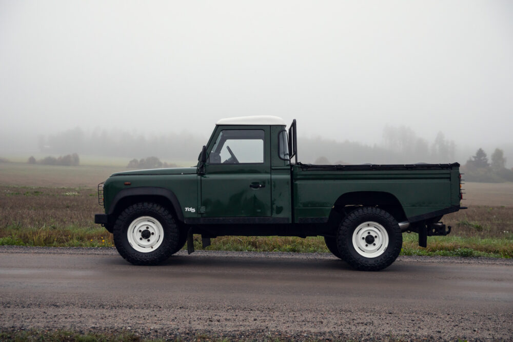 Green pickup truck on foggy rural road.