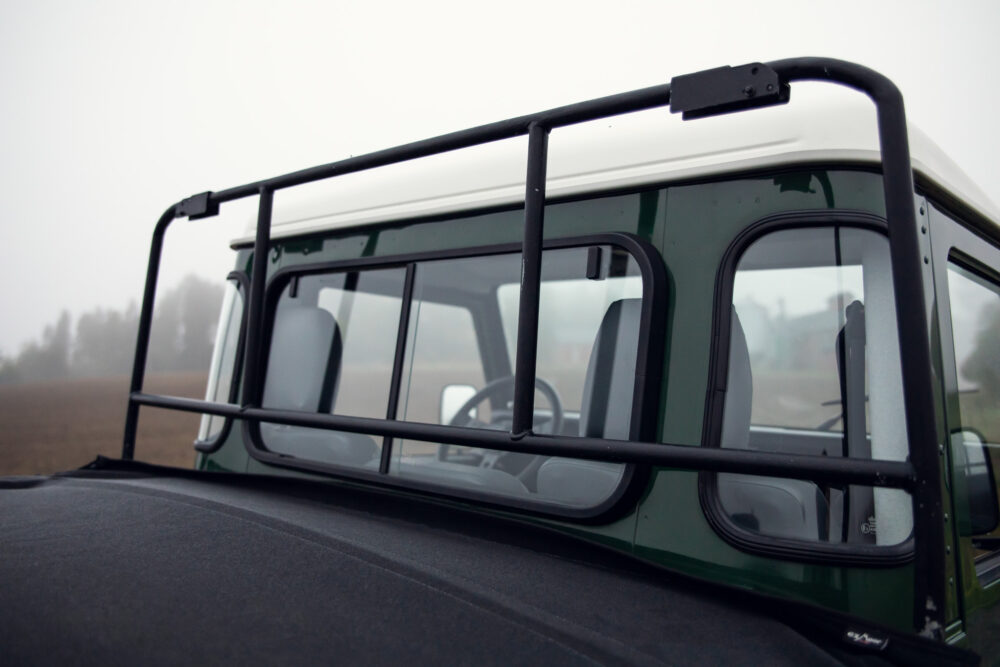 Green off-road vehicle with roof rack in foggy weather.