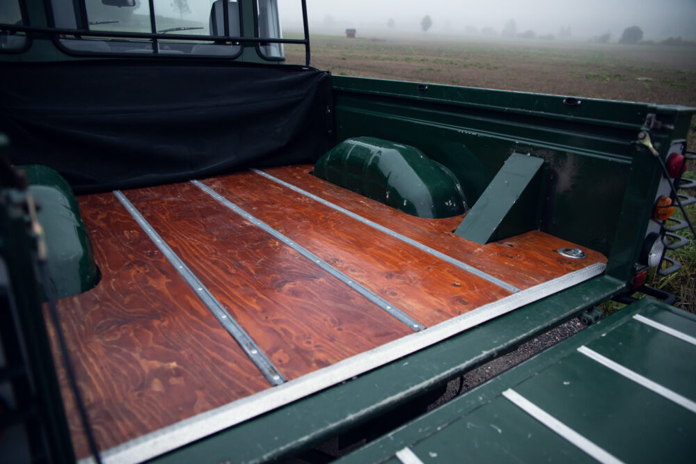 Polished wooden bed of green truck in foggy field.