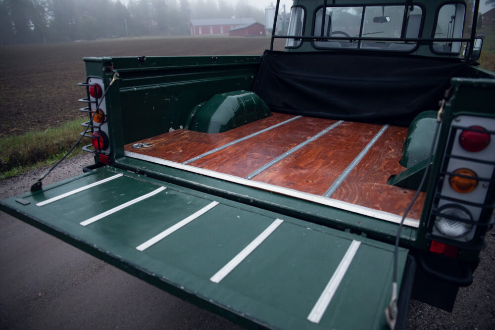 Open cargo bed of green truck in misty rural setting.