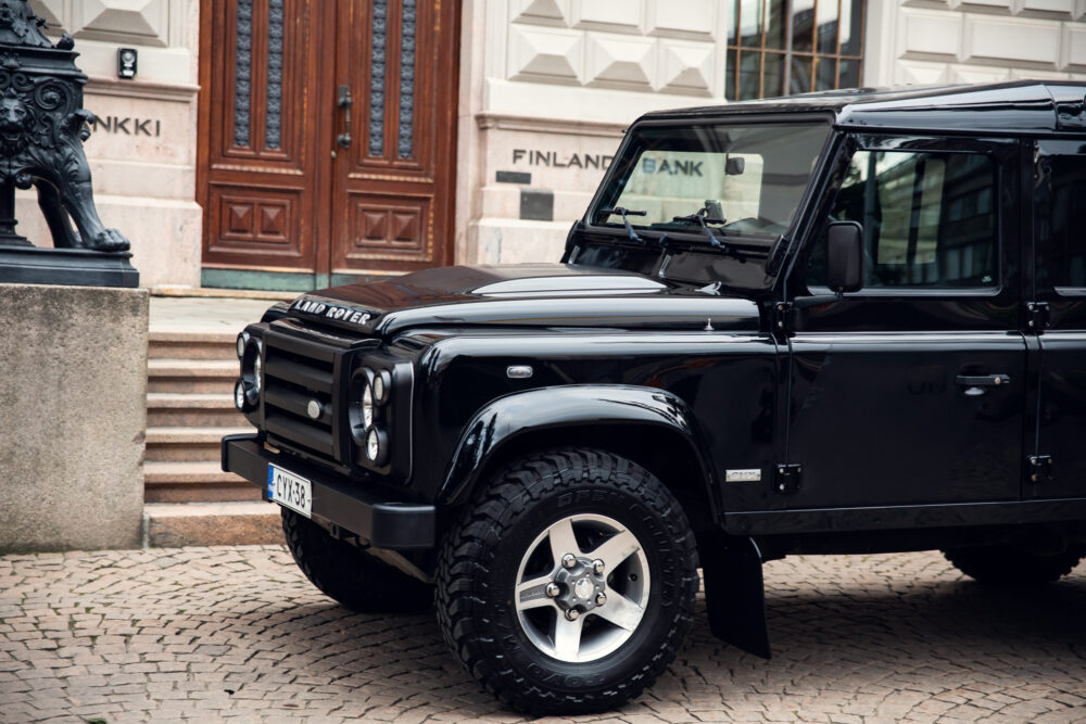 Black Land Rover Defender parked in front of bank.