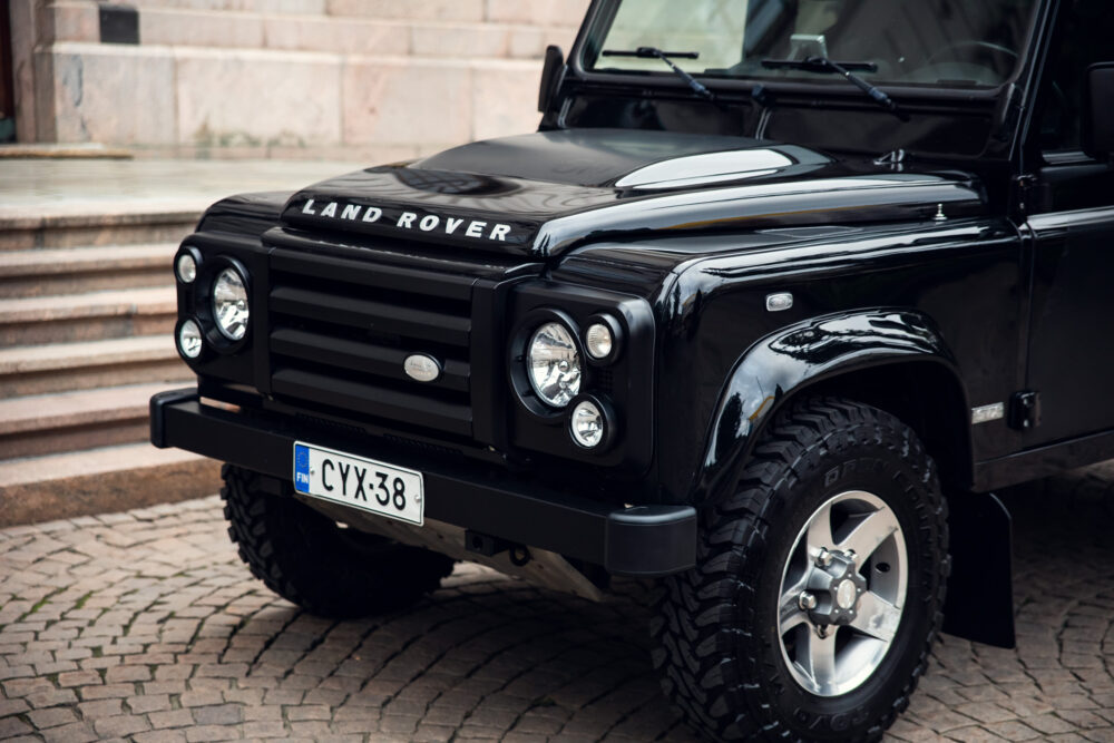 Black Land Rover Defender parked by stone stairs.