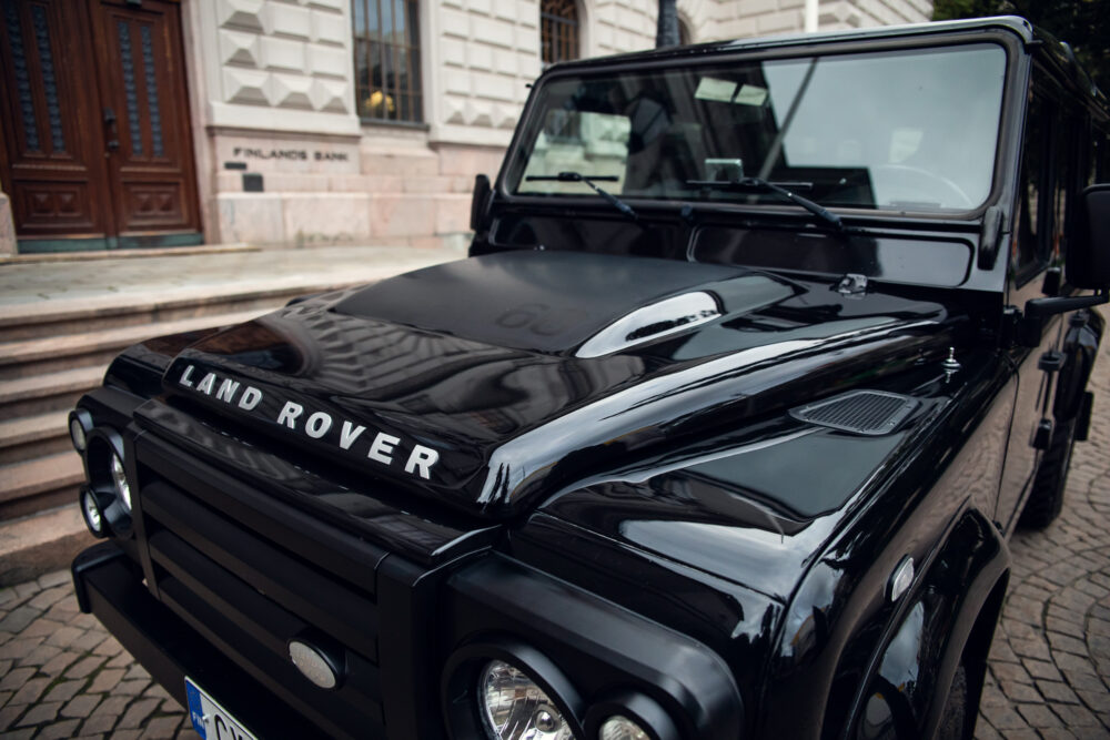 Black Land Rover parked near historic building.