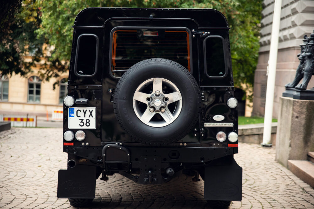 Rear view of a black Land Rover Defender with spare tire.