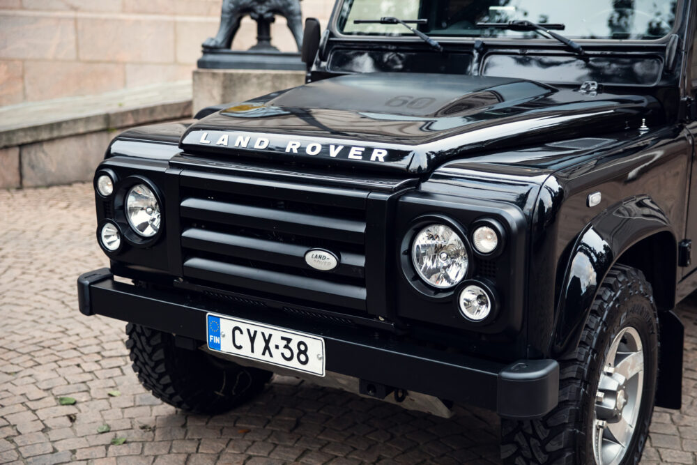 Black Land Rover Defender parked on cobblestone street.