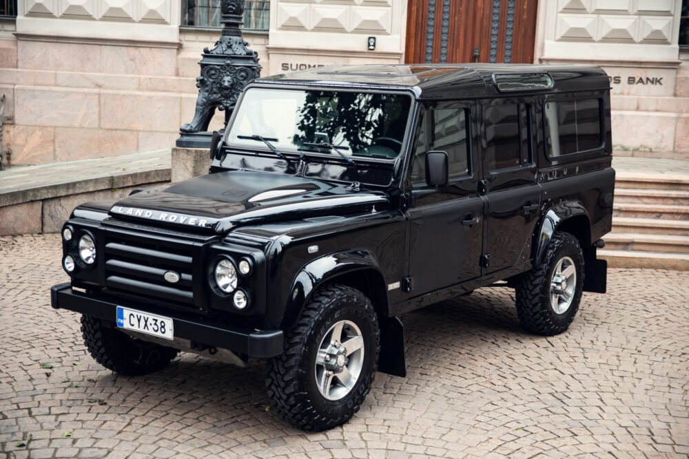 Black Land Rover Defender parked near ornate building.