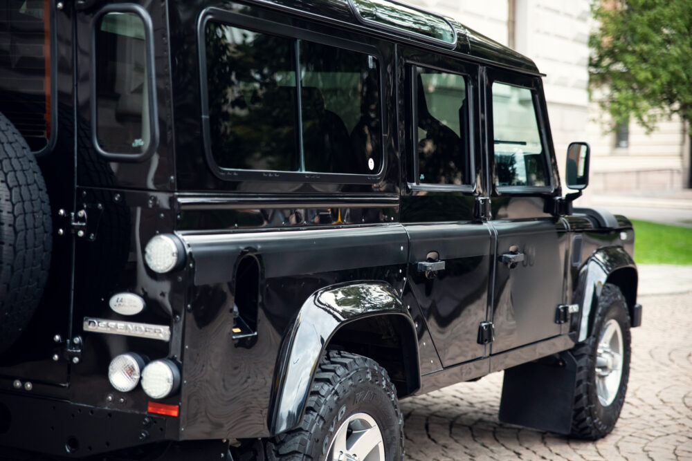 Black Land Rover Defender parked on city street.