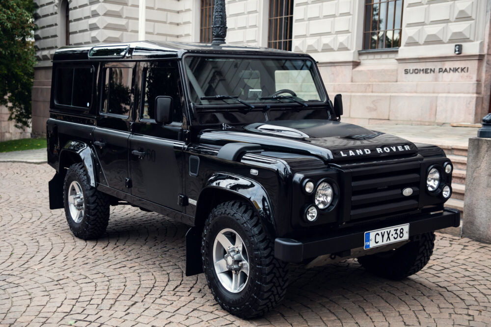 Black Land Rover Defender parked on cobblestone.