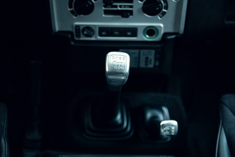 Car's manual gear shift knob in dark interior.