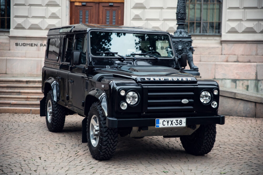 Black Land Rover Defender in front of building.