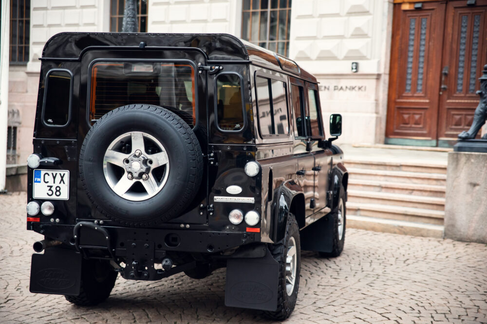 Black Land Rover Defender parked near historic building.