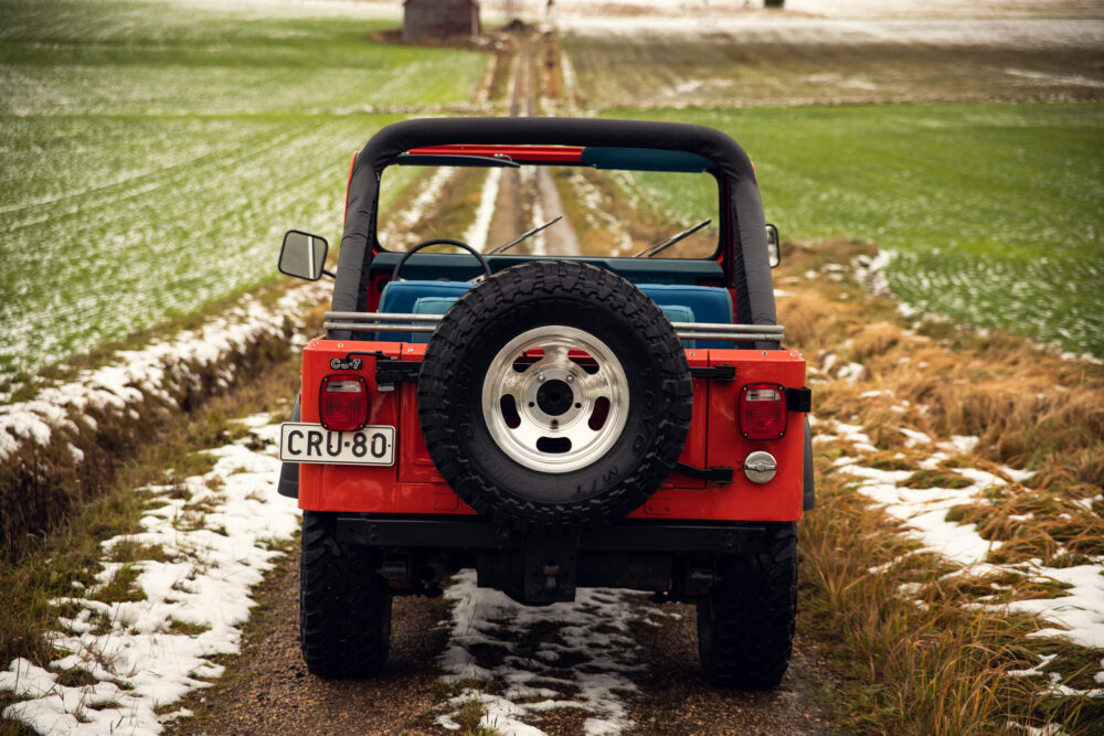 Red jeep on snowy trail in countryside