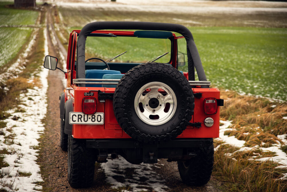 Red Jeep with spare tire on snowy country road