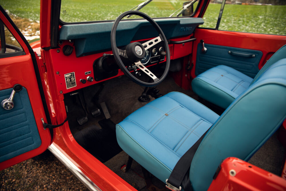 Vintage red car interior with blue seats and steering wheel