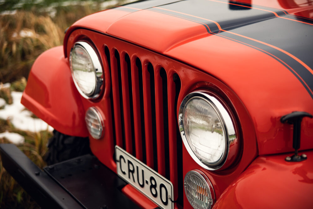 Close-up of red vintage jeep grille and headlights