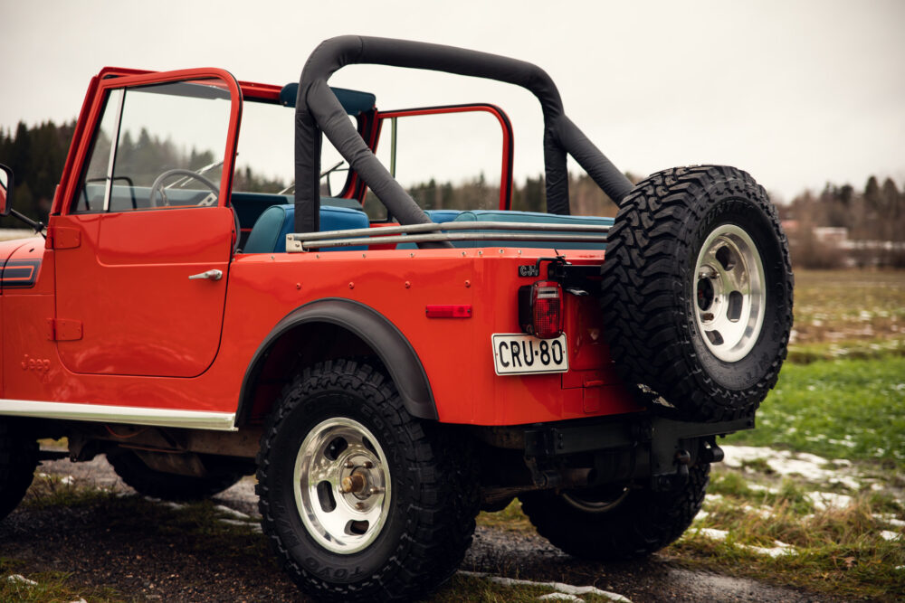 Red Jeep with spare tire outdoors on cloudy day